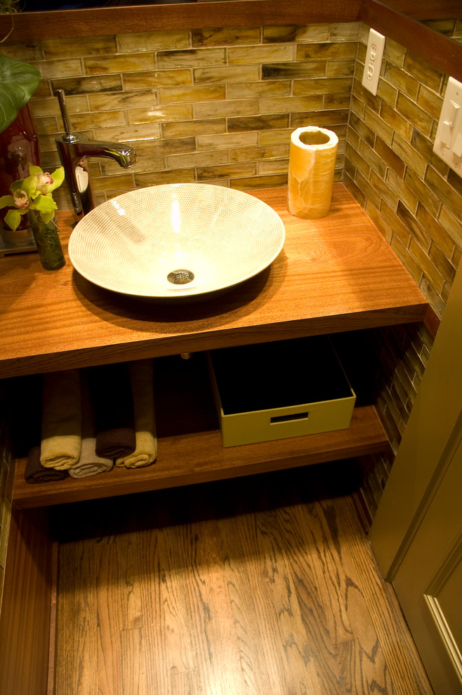 Small contemporary bathroom in Dallas with a vessel sink, open cabinets, medium wood cabinets, wood benchtops, brown tile, medium hardwood floors and brown walls.