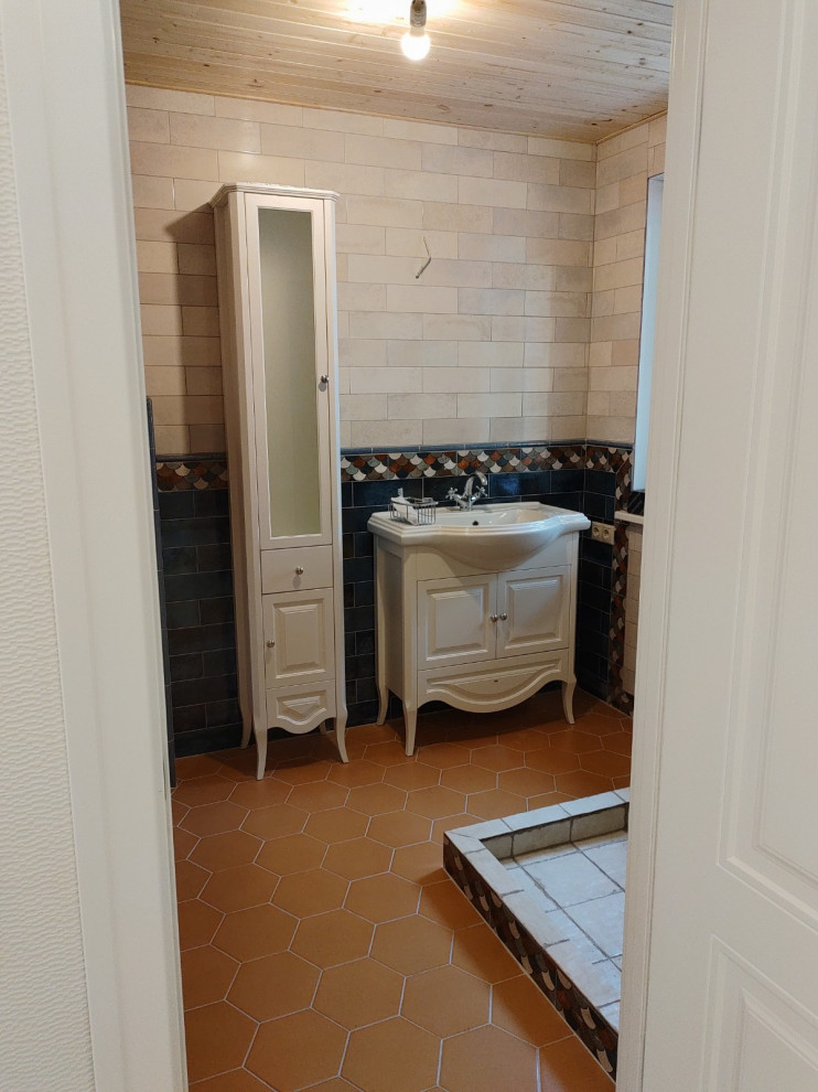 Cette image montre un WC suspendu chalet avec un placard avec porte à panneau encastré, des portes de placard blanches, un carrelage bleu, des carreaux de céramique, un mur beige, un sol en carrelage de porcelaine, un lavabo posé, un sol orange, meuble-lavabo sur pied et un plafond en lambris de bois.