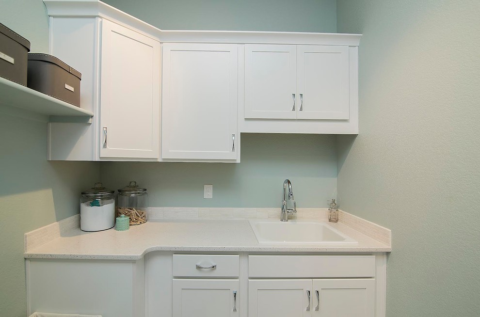 This is an example of a small transitional single-wall dedicated laundry room in Denver with a drop-in sink, shaker cabinets, white cabinets, quartz benchtops and green walls.