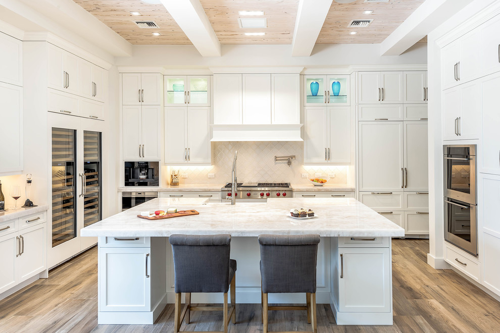 Inspiration for a transitional kitchen in Miami with shaker cabinets, white cabinets, white splashback, stainless steel appliances, with island and beige floor.