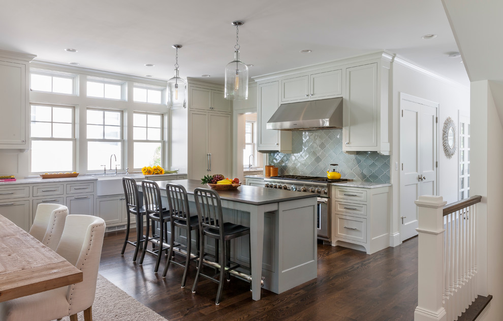 This is an example of a traditional l-shaped eat-in kitchen in Minneapolis with a farmhouse sink, shaker cabinets, white cabinets, blue splashback and stainless steel appliances.