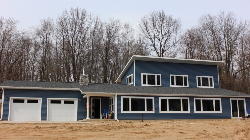 Large transitional two-storey blue exterior in Orange County with vinyl siding and a flat roof.