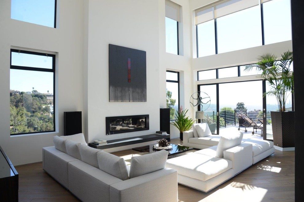 Large modern formal loft-style living room in Los Angeles with white walls, light hardwood floors, a standard fireplace, no tv, beige floor and vaulted.