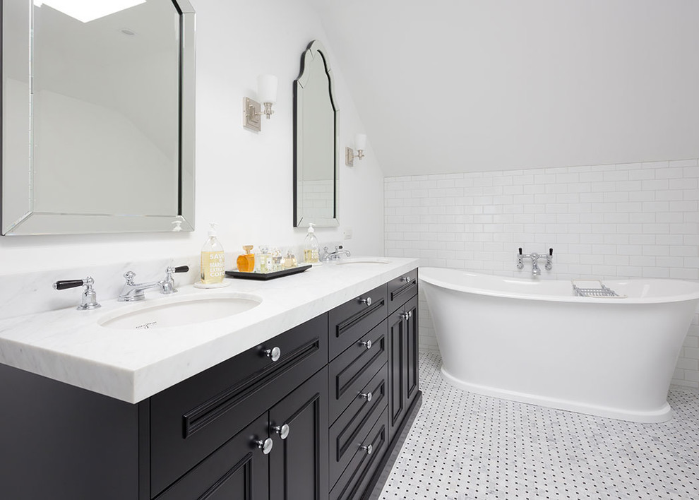 This is an example of a traditional bathroom in Auckland with recessed-panel cabinets, black cabinets, a freestanding tub, white walls, mosaic tile floors and an undermount sink.