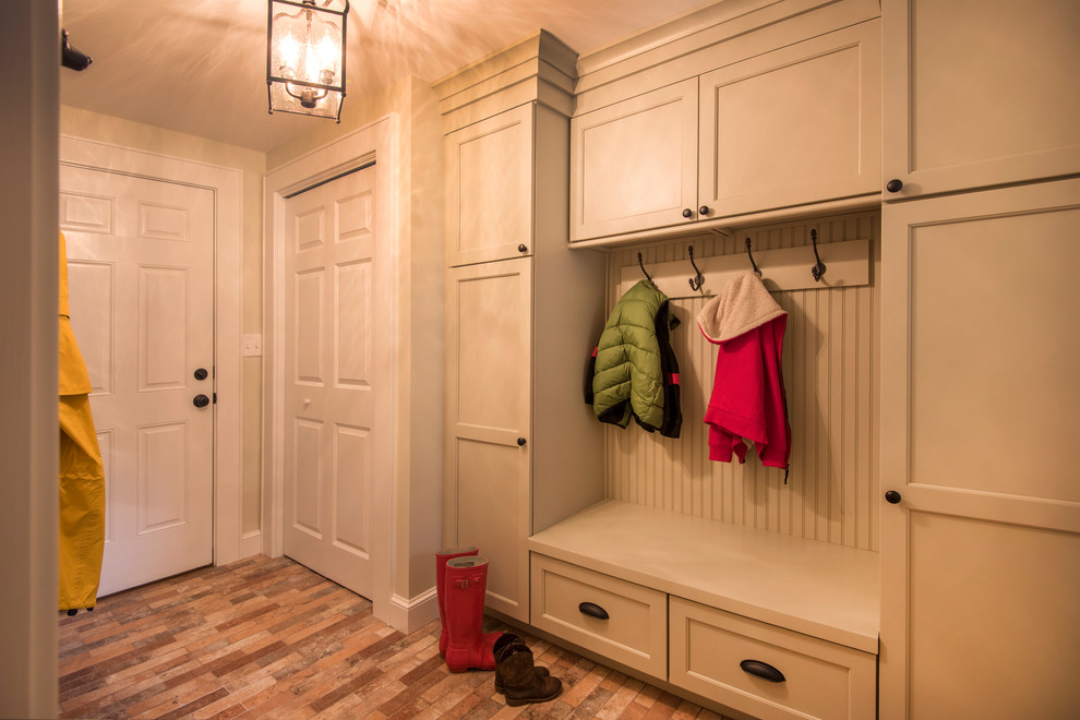 Design ideas for a large country mudroom in Boston with green walls, ceramic floors and brown floor.