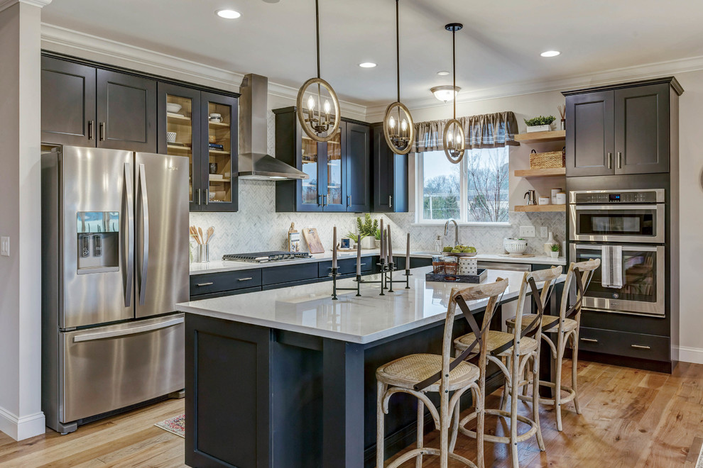 Transitional l-shaped light wood floor and brown floor eat-in kitchen photo in St Louis with an undermount sink, shaker cabinets, blue cabinets, quartz countertops, white backsplash, marble backsplash, stainless steel appliances, an island and white countertops