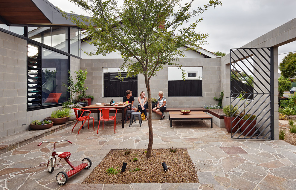 This is an example of a contemporary patio in Melbourne with natural stone pavers and no cover.