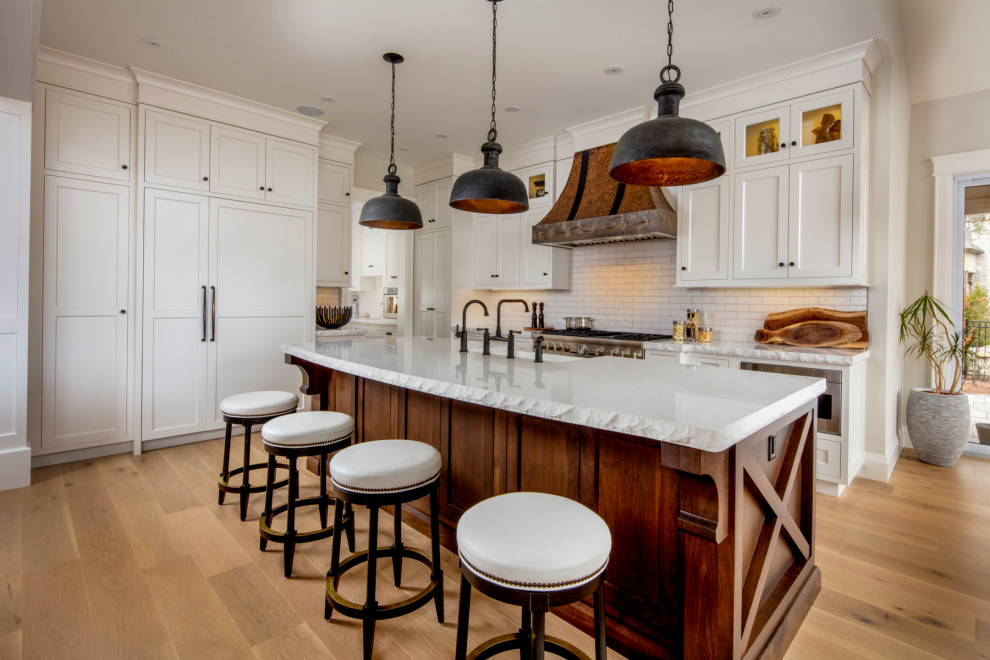 Eat-in kitchen - large rustic l-shaped light wood floor and beige floor eat-in kitchen idea in Toronto with a farmhouse sink, shaker cabinets, white cabinets, quartz countertops, white backsplash, subway tile backsplash, paneled appliances, an island and white countertops