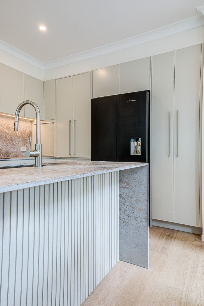 Inspiration for a large modern l-shaped open plan kitchen in Brisbane with a double-bowl sink, raised-panel cabinets, grey cabinets, engineered stone countertops, engineered quartz splashback, black appliances, light hardwood flooring, an island and brown floors.