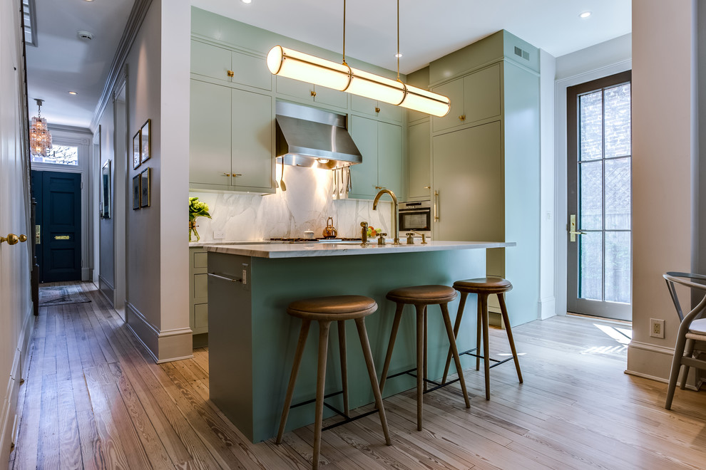 Photo of a mid-sized transitional l-shaped kitchen in DC Metro with an integrated sink, flat-panel cabinets, green cabinets, quartzite benchtops, stainless steel appliances, light hardwood floors, with island and brown floor.