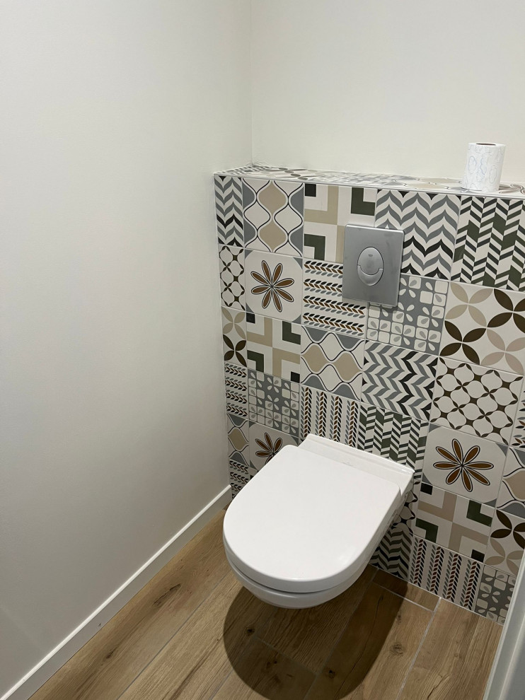 Design ideas for a modern cloakroom in Clermont-Ferrand with a wall mounted toilet, multi-coloured tiles, cement tiles and wood-effect flooring.