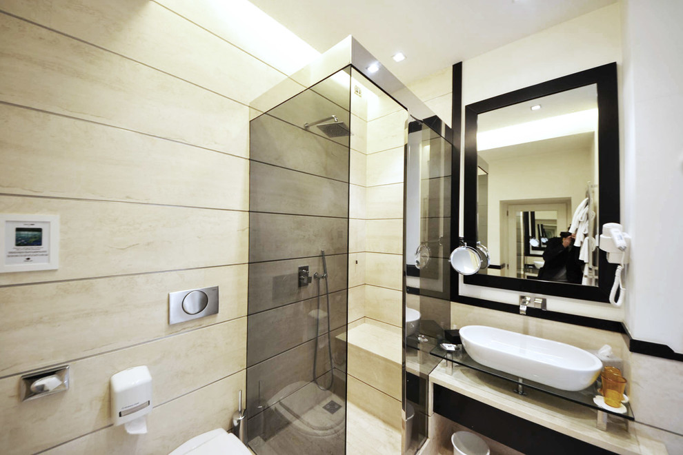Photo of a small modern bathroom in Rome with a vessel sink, glass benchtops, a corner shower, beige tile, stone slab, beige walls and travertine floors.