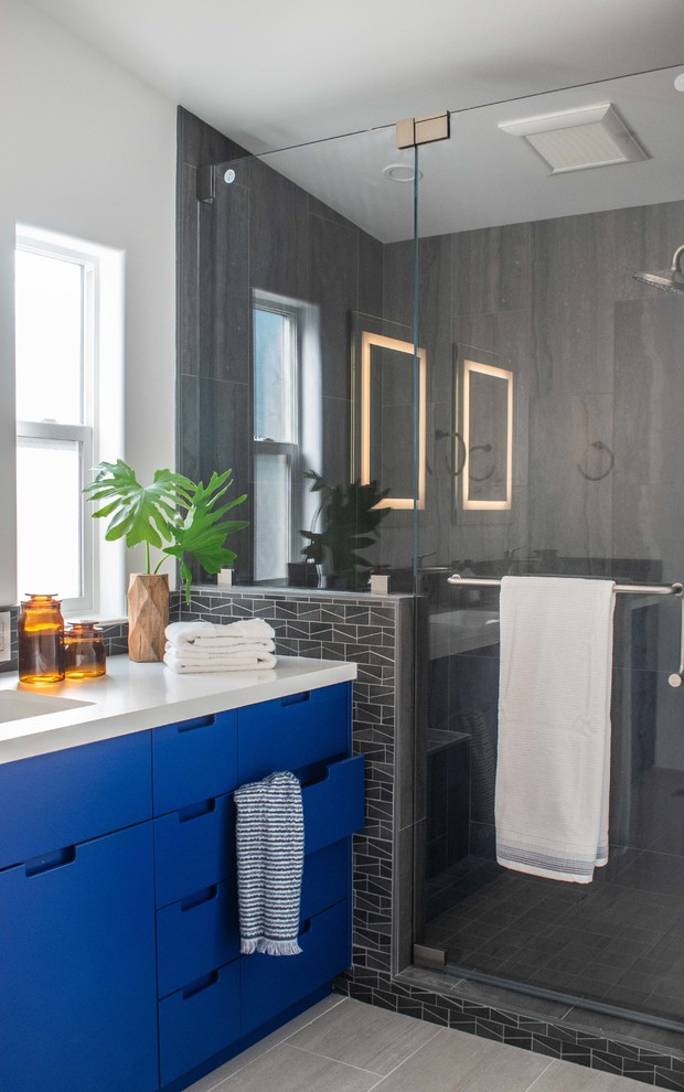Inspiration for a mid-sized modern master bathroom in San Francisco with flat-panel cabinets, blue cabinets, an alcove shower, a one-piece toilet, gray tile, porcelain tile, grey walls, porcelain floors, an undermount sink, engineered quartz benchtops, grey floor, a hinged shower door and white benchtops.