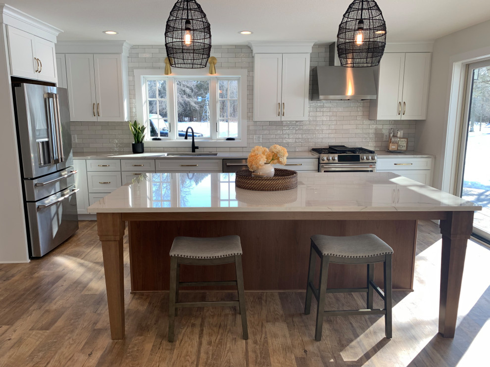 Inspiration for a large transitional l-shaped vinyl floor and brown floor eat-in kitchen remodel with an undermount sink, shaker cabinets, white cabinets, quartz countertops, stainless steel appliances, an island and gray countertops