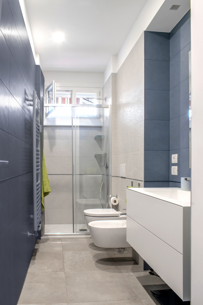 Exempel på ett mellanstort modernt badrum med dusch, med släta luckor, vita skåp, en dusch i en alkov, en vägghängd toalettstol, blå kakel, porslinskakel, blå väggar, klinkergolv i porslin, ett integrerad handfat, grått golv och dusch med skjutdörr