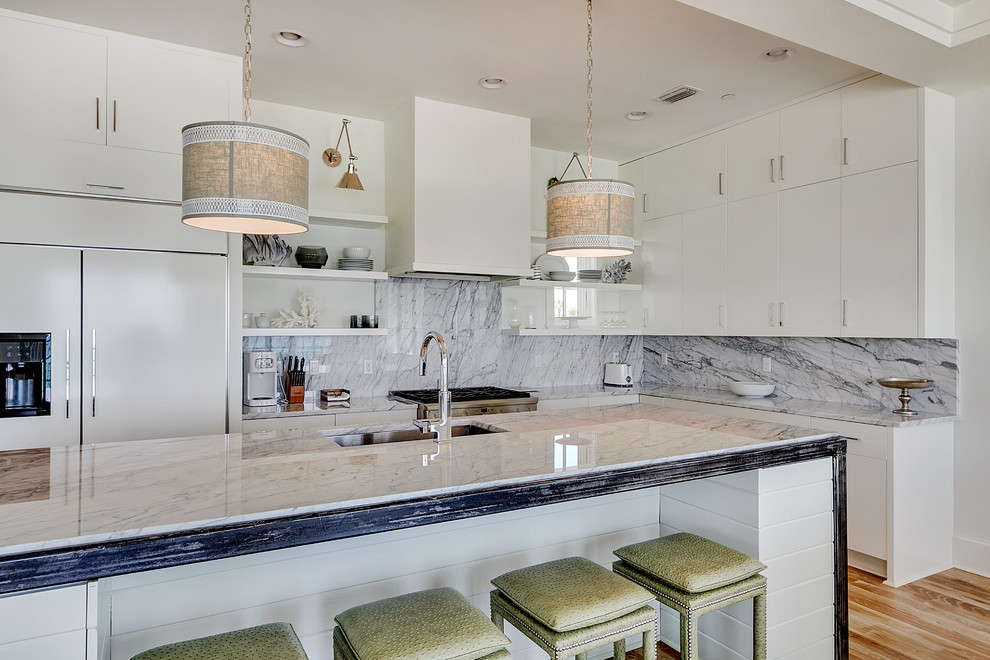 Beach style l-shaped open plan kitchen in Miami with an undermount sink, flat-panel cabinets, white cabinets, grey splashback, stone slab splashback, panelled appliances and medium hardwood floors.