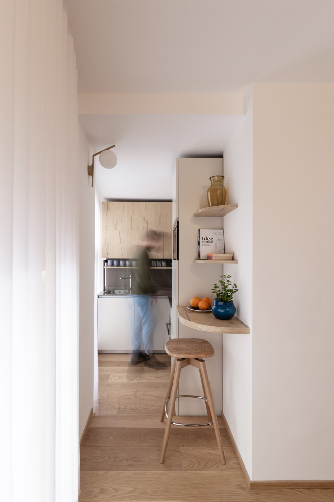 Immagine di una cucina a L contemporanea con ante lisce, paraspruzzi grigio, parquet chiaro e top grigio