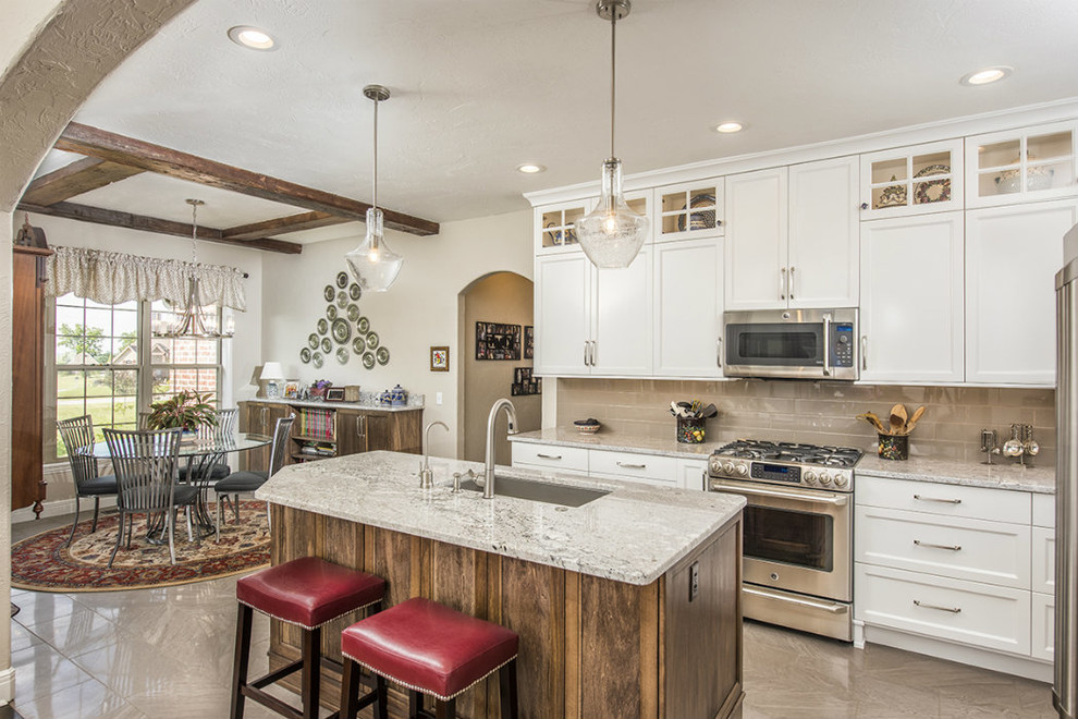 Mid-sized transitional l-shaped marble floor and brown floor kitchen photo with an undermount sink, shaker cabinets, white cabinets, granite countertops, brown backsplash, subway tile backsplash, stainless steel appliances and an island