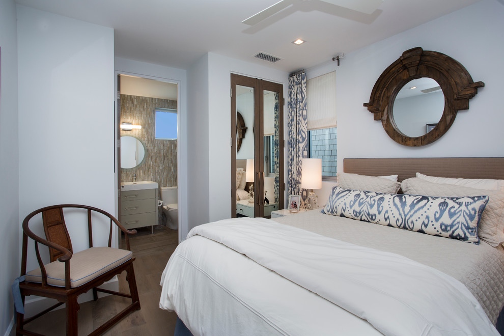 Inspiration for a beach style guest bedroom in Orange County with white walls and light hardwood floors.