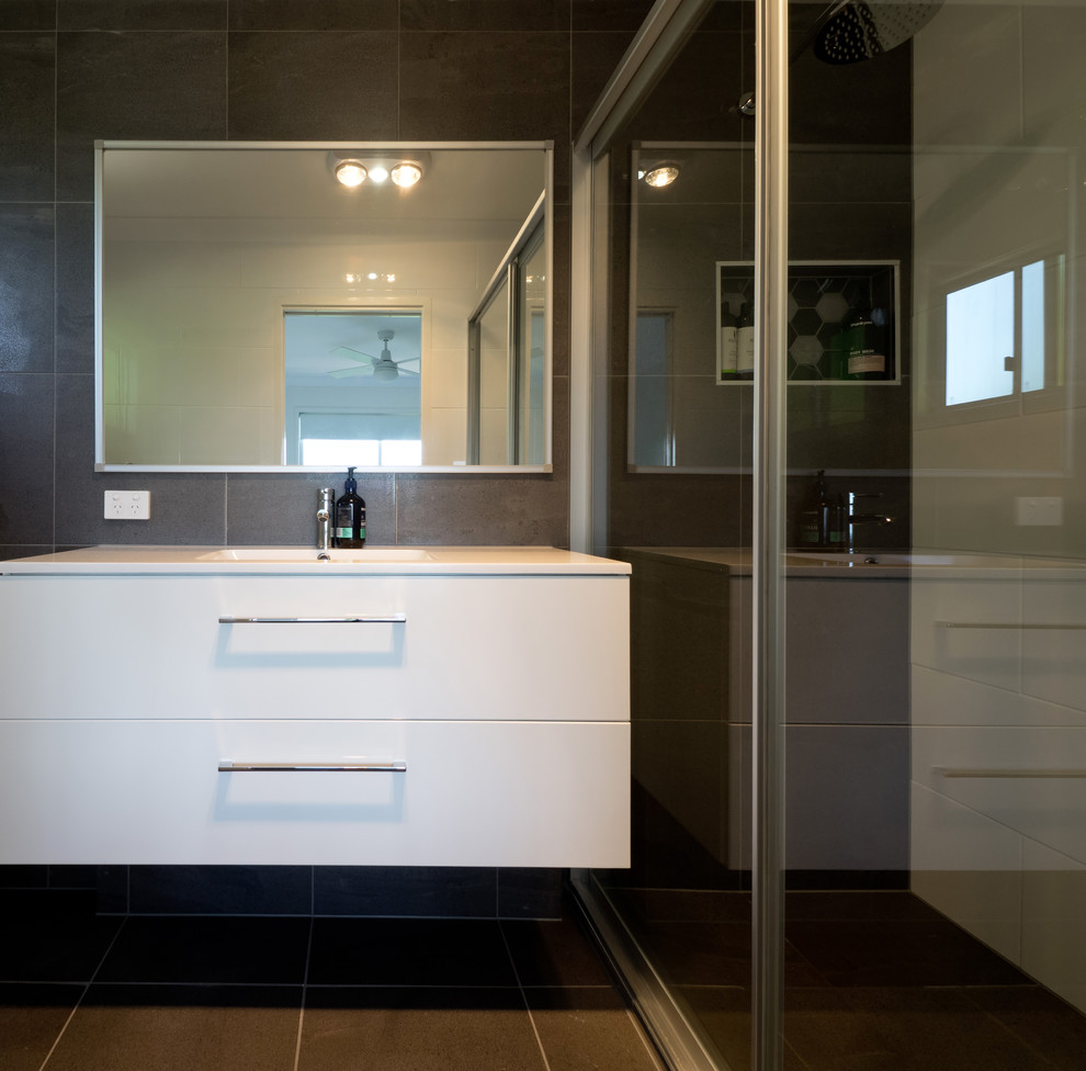 Design ideas for a mid-sized contemporary bathroom in Brisbane with flat-panel cabinets, white cabinets, a corner shower, brown tile, ceramic tile, brown walls, ceramic floors, an integrated sink, brown floor and a hinged shower door.