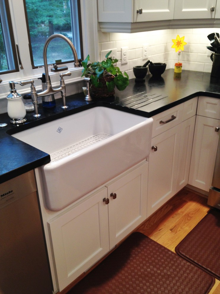 Inspiration for a transitional kitchen in Raleigh with a farmhouse sink, shaker cabinets, white cabinets, soapstone benchtops, white splashback, subway tile splashback, stainless steel appliances and medium hardwood floors.