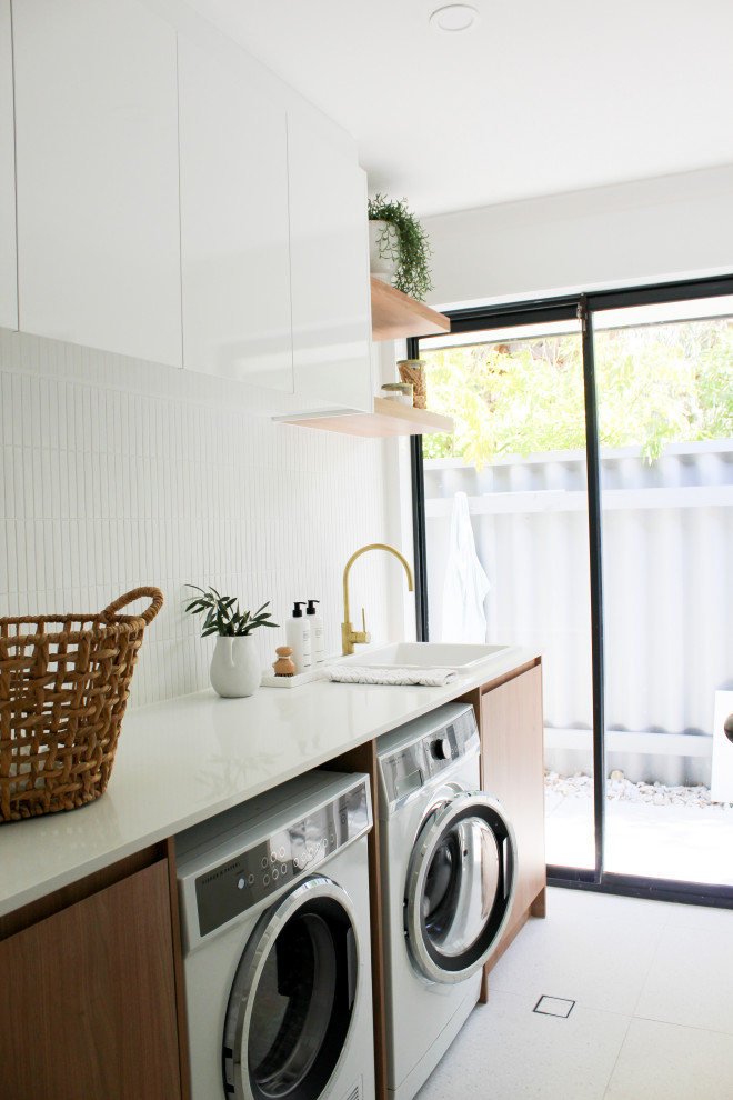Mid-sized country single-wall dedicated laundry room in Perth with a farmhouse sink, flat-panel cabinets, dark wood cabinets, quartz benchtops, white walls, porcelain floors, a side-by-side washer and dryer, multi-coloured floor and white benchtop.
