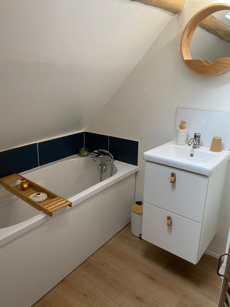 Kleines Nordisches Duschbad mit Lamellenschränken, Badewanne in Nische, Wandtoilette, blauen Fliesen, weißer Wandfarbe, hellem Holzboden, Wandwaschbecken, weißer Waschtischplatte, Einzelwaschbecken, schwebendem Waschtisch und freigelegten Dachbalken in Toulouse