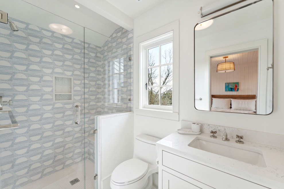 Пример оригинального дизайна: ванная комната в морском стиле с белыми фасадами, душем без бортиков, цементной плиткой, врезной раковиной, душем с распашными дверями, встроенной тумбой, фасадами в стиле шейкер, полом из мозаичной плитки, столешницей из искусственного кварца, белым полом, белой столешницей и тумбой под одну раковину