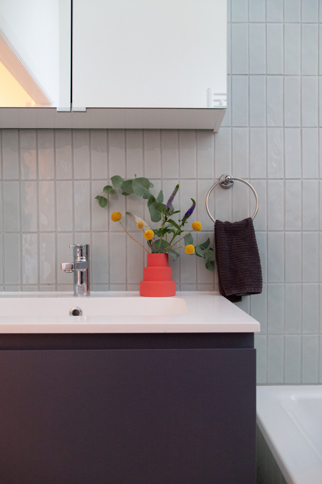 Стильный дизайн: узкая и длинная серо-белая ванная комната среднего размера в современном стиле с фасадами с выступающей филенкой, серыми фасадами, накладной ванной, душем над ванной, раздельным унитазом, зеленой плиткой, керамической плиткой, белыми стенами, полом из керамической плитки, душевой кабиной, монолитной раковиной, столешницей из ламината, серым полом, открытым душем, белой столешницей, тумбой под одну раковину, подвесной тумбой и многоуровневым потолком - последний тренд