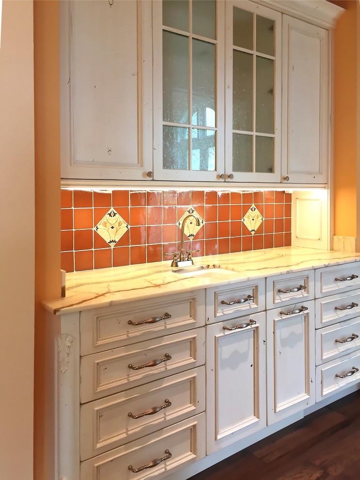 This is an example of a mid-sized mediterranean single-wall wet bar in Miami with an undermount sink, white cabinets, onyx benchtops, multi-coloured splashback, terra-cotta splashback, medium hardwood floors and multi-coloured benchtop.