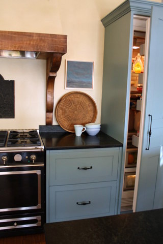 This is an example of a mid-sized country l-shaped open plan kitchen in Other with a farmhouse sink, shaker cabinets, blue cabinets, granite benchtops, yellow splashback, black appliances, dark hardwood floors and with island.