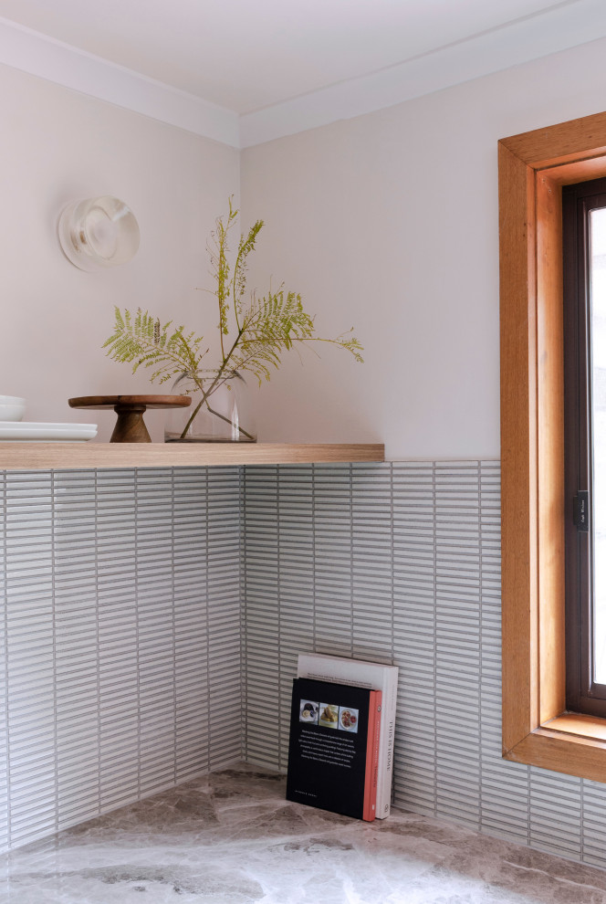 This is an example of a mid-sized midcentury u-shaped kitchen pantry in Melbourne with a single-bowl sink, flat-panel cabinets, green cabinets, limestone benchtops, white splashback, mosaic tile splashback, black appliances, slate floors, a peninsula, brown floor and beige benchtop.