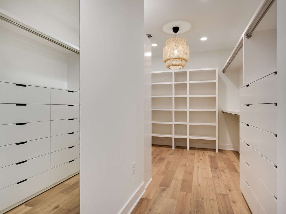 Large country gender-neutral walk-in wardrobe in Austin with light hardwood floors.