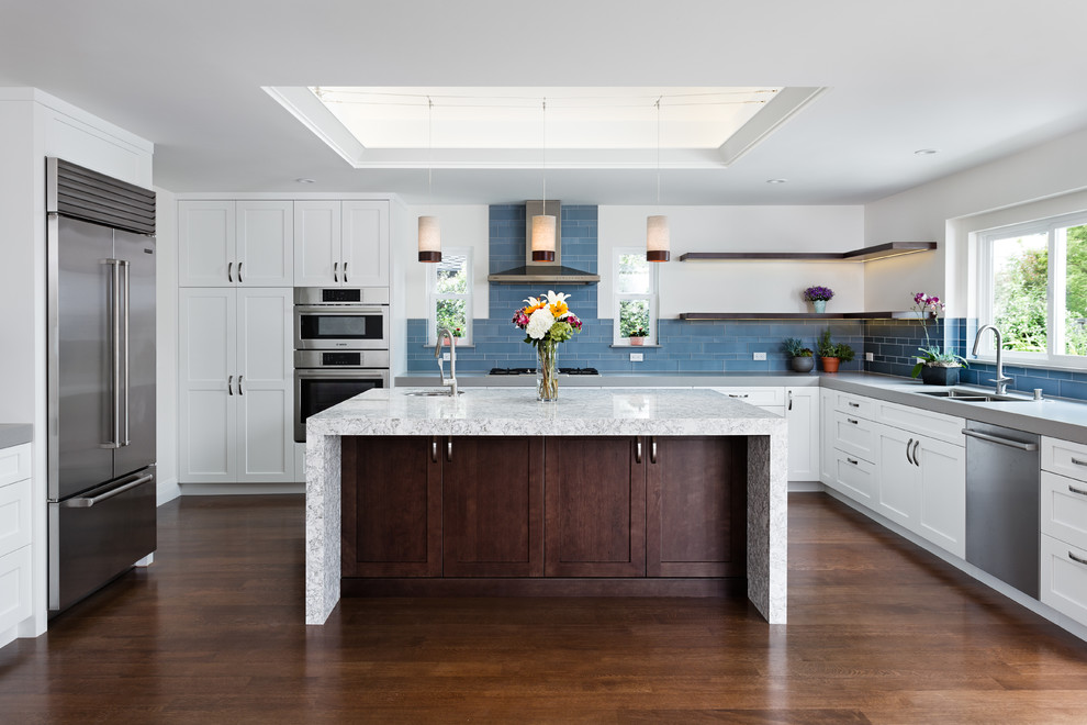 Mid-sized transitional u-shaped eat-in kitchen in San Francisco with an undermount sink, shaker cabinets, white cabinets, quartz benchtops, blue splashback, glass tile splashback, stainless steel appliances, dark hardwood floors, with island and brown floor.