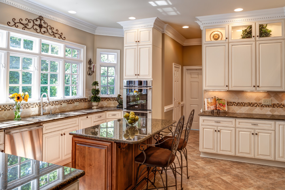 Photo of a traditional kitchen in Charlotte with raised-panel cabinets, beige cabinets, beige splashback, stainless steel appliances and limestone splashback.