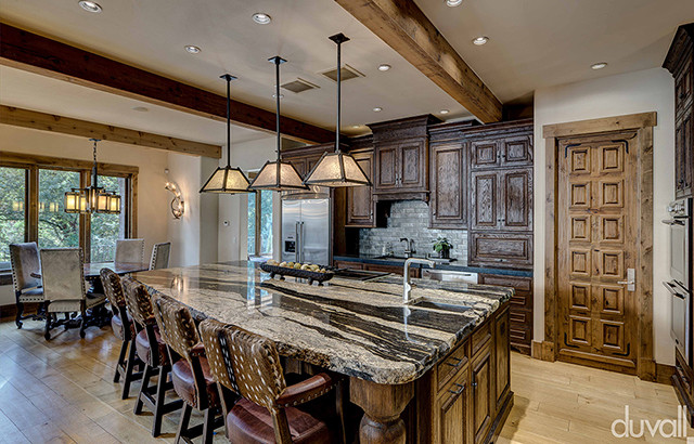 Kitchen - rustic light wood floor kitchen idea with brown cabinets, granite countertops, gray backsplash, brick backsplash, stainless steel appliances and an island