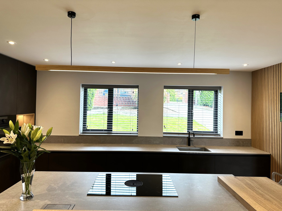 This is an example of a medium sized contemporary l-shaped kitchen/diner in Other with an integrated sink, flat-panel cabinets, black appliances, porcelain flooring, an island and feature lighting.
