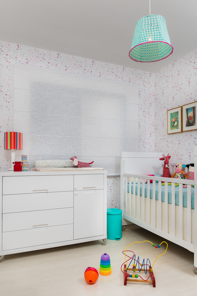 This is an example of a small contemporary nursery in Other with multi-coloured walls, light hardwood floors and beige floor.