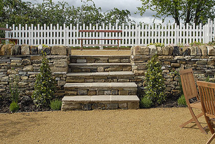 Design ideas for a large eclectic backyard full sun garden in London with a retaining wall and natural stone pavers.