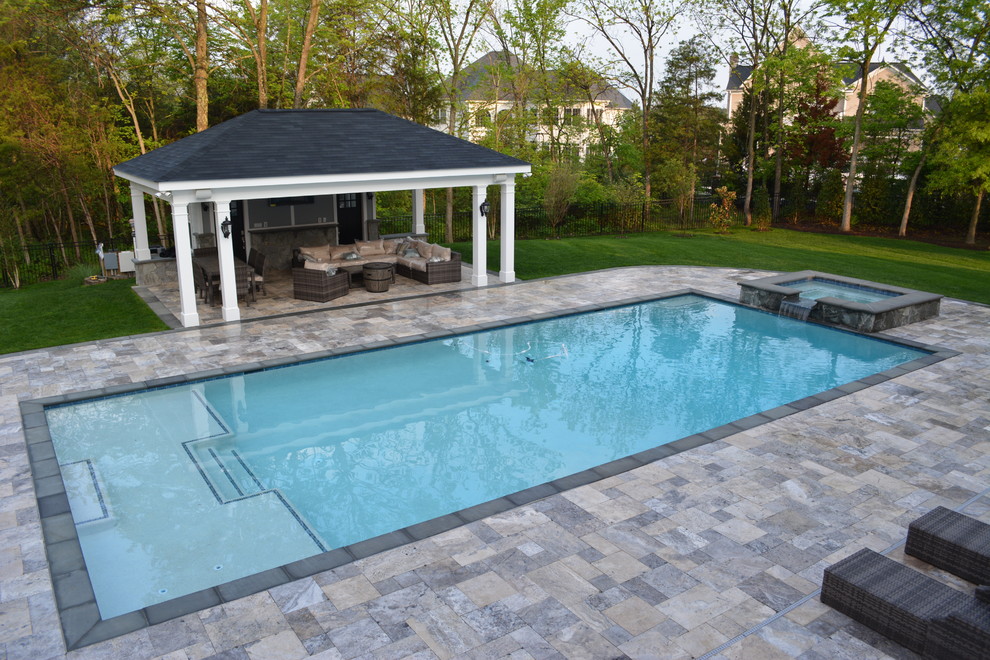 This is an example of a large contemporary backyard rectangular lap pool in DC Metro with a water feature and natural stone pavers.
