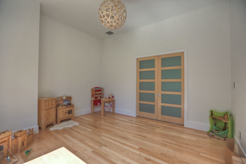 Photo of a mid-sized contemporary gender-neutral kids' playroom for kids 4-10 years old in Houston with white walls and light hardwood floors.