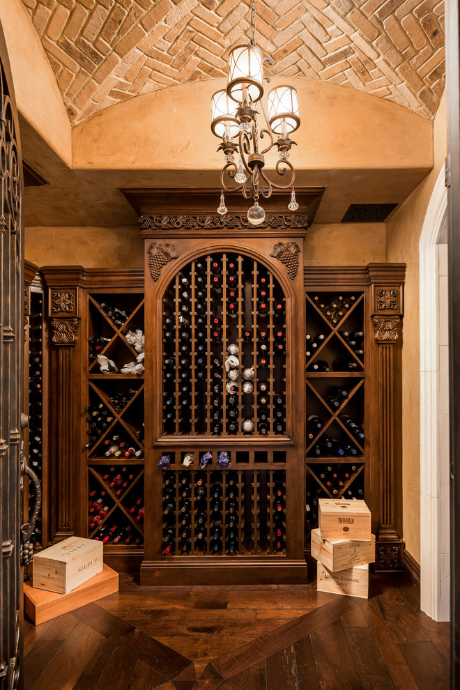 This is an example of a mediterranean wine cellar in Phoenix with dark hardwood floors, diamond bins and brown floor.