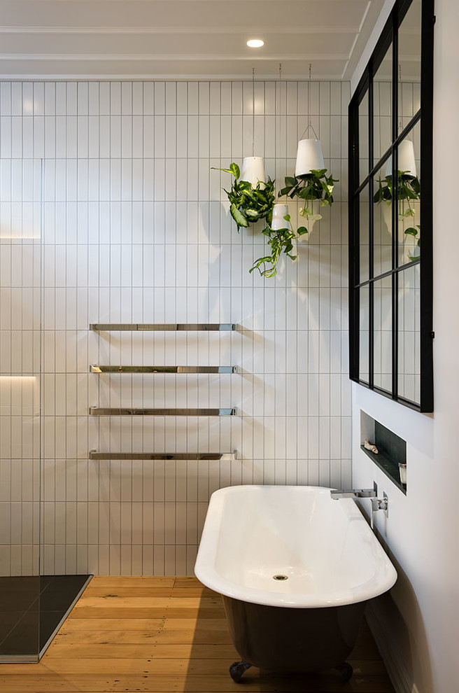 Design ideas for a mid-sized midcentury bathroom in Auckland with glass-front cabinets, white cabinets, a claw-foot tub, a curbless shower, a one-piece toilet, white tile, ceramic tile, white walls, medium hardwood floors, a wall-mount sink, marble benchtops and an open shower.