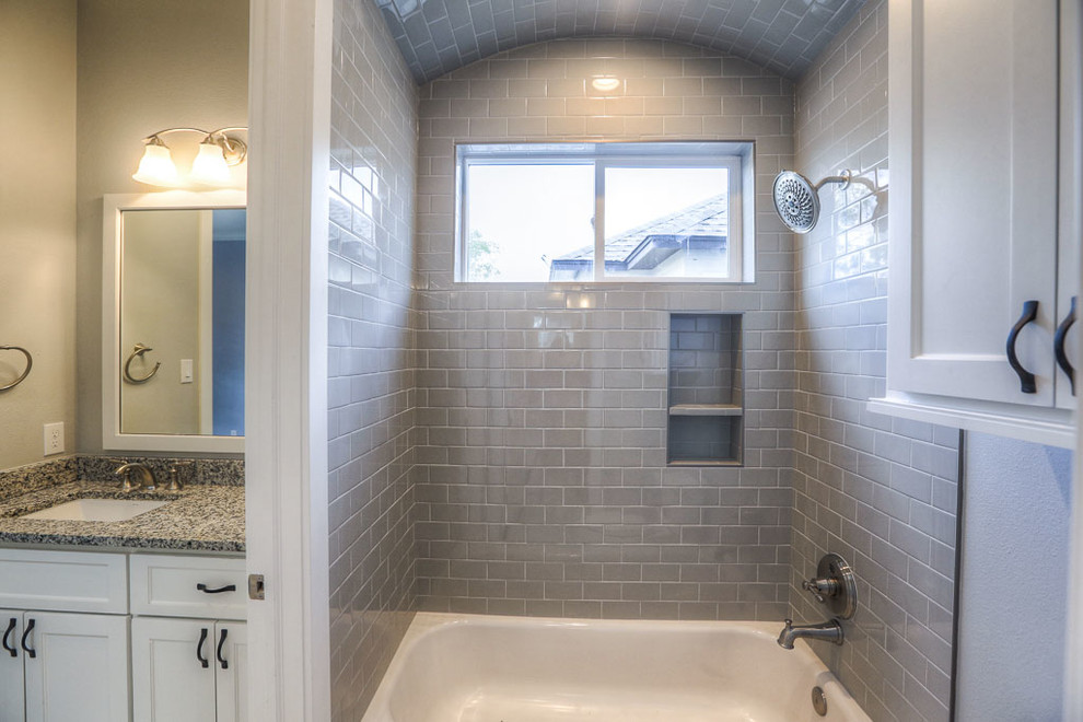 This is an example of a mid-sized arts and crafts master bathroom in Houston with shaker cabinets, white cabinets, an alcove tub, a shower/bathtub combo, a two-piece toilet, gray tile, glass tile, grey walls, an undermount sink and granite benchtops.
