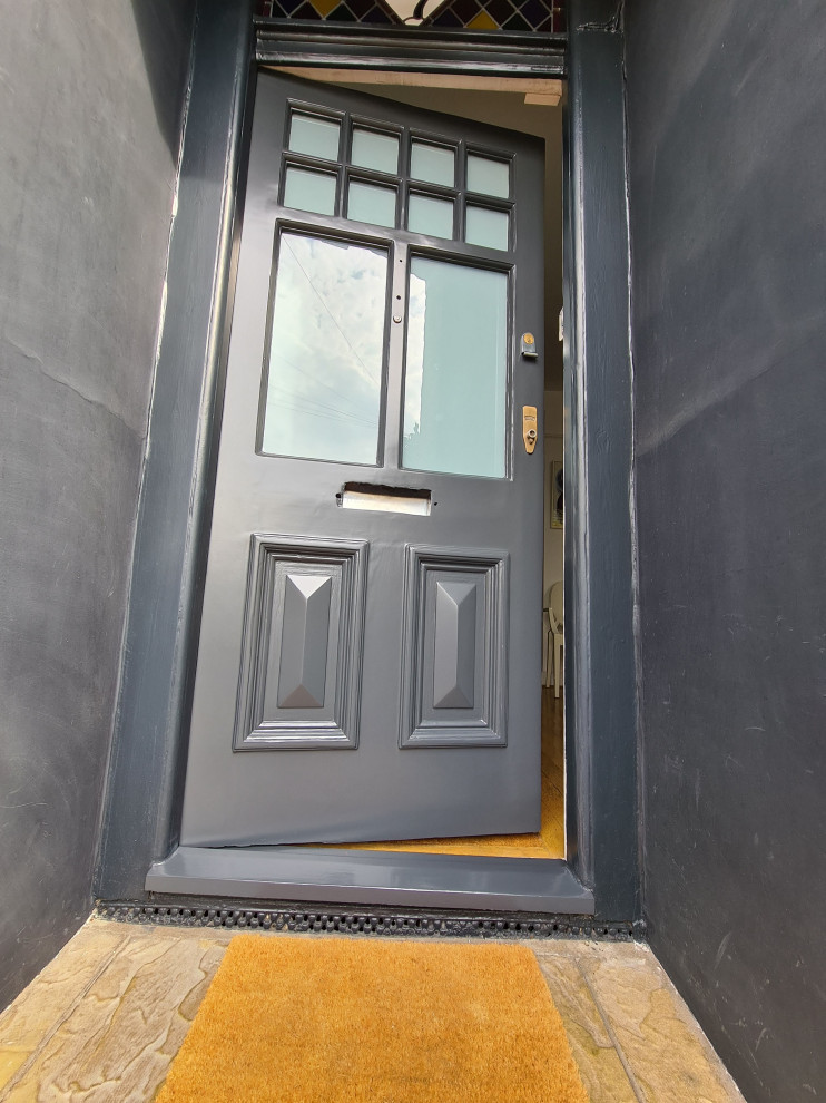 This is an example of a mid-sized traditional front door in London with black walls, dark hardwood floors, a single front door, a black front door, brown floor and recessed.