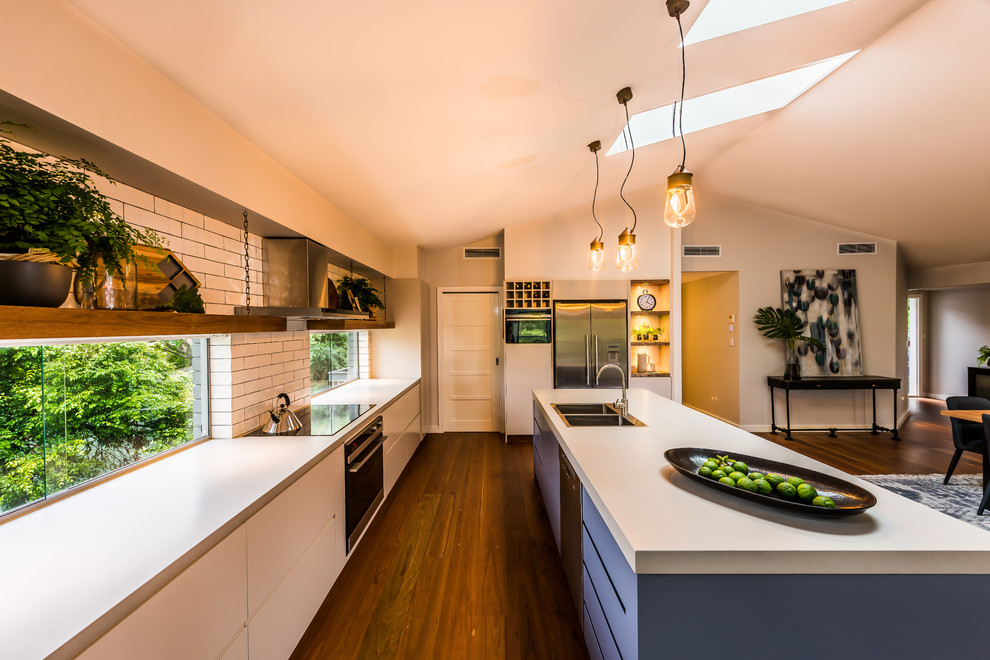 Photo of a large contemporary u-shaped eat-in kitchen in Sydney with an undermount sink, flat-panel cabinets, beige cabinets, quartz benchtops, white splashback, subway tile splashback, stainless steel appliances, porcelain floors, with island and orange floor.
