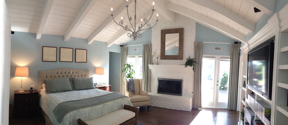 Photo of a large transitional master bedroom in San Diego with blue walls, dark hardwood floors, a standard fireplace, a brick fireplace surround and brown floor.