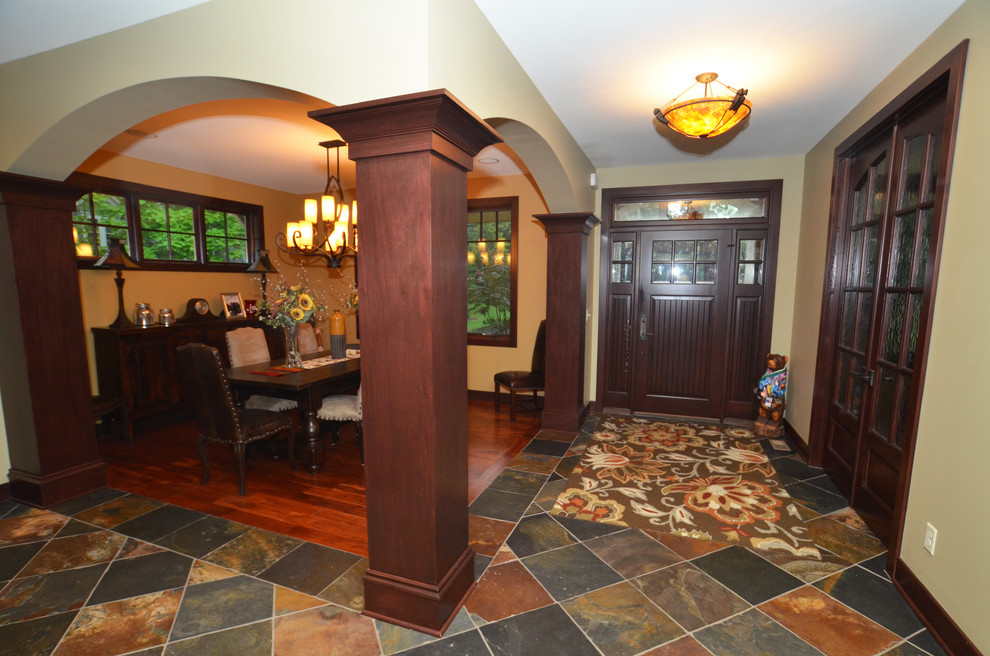 This is an example of a traditional entryway in Milwaukee with slate floors, a single front door and a dark wood front door.
