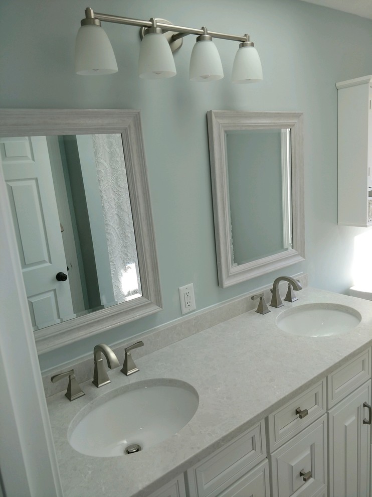 Photo of a mid-sized traditional 3/4 bathroom in Providence with raised-panel cabinets, white cabinets, an alcove tub, a shower/bathtub combo, a two-piece toilet, grey walls, dark hardwood floors, an undermount sink, brown floor, a shower curtain and white benchtops.