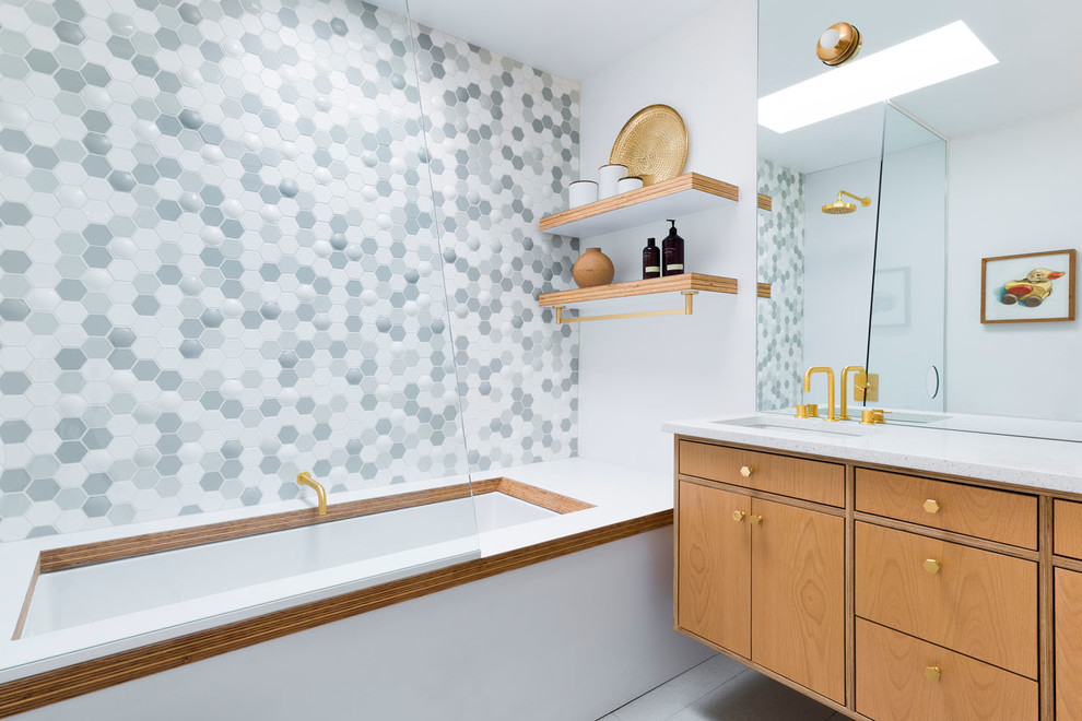 Photo of a mid-sized midcentury bathroom in Portland with flat-panel cabinets, light wood cabinets, an undermount tub, a shower/bathtub combo, gray tile, multi-coloured tile, white tile, mosaic tile, white walls, an undermount sink, grey floor, white benchtops, solid surface benchtops and an open shower.